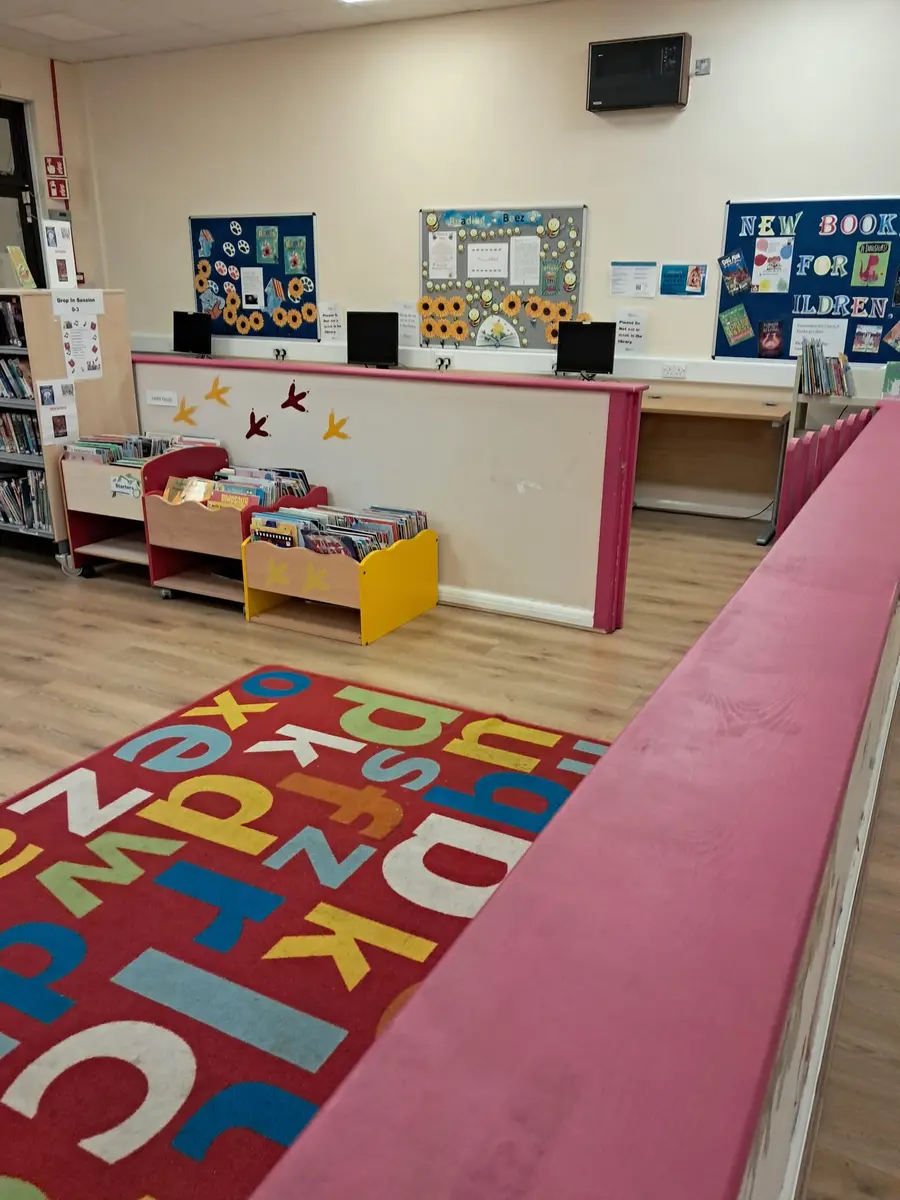 A classroom at the centre, with display boards, a low bookcase and a lettered play mat