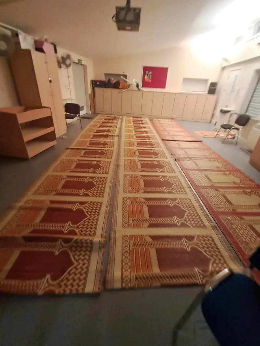 A teaching room with prayer mats laid in rows across the floor
